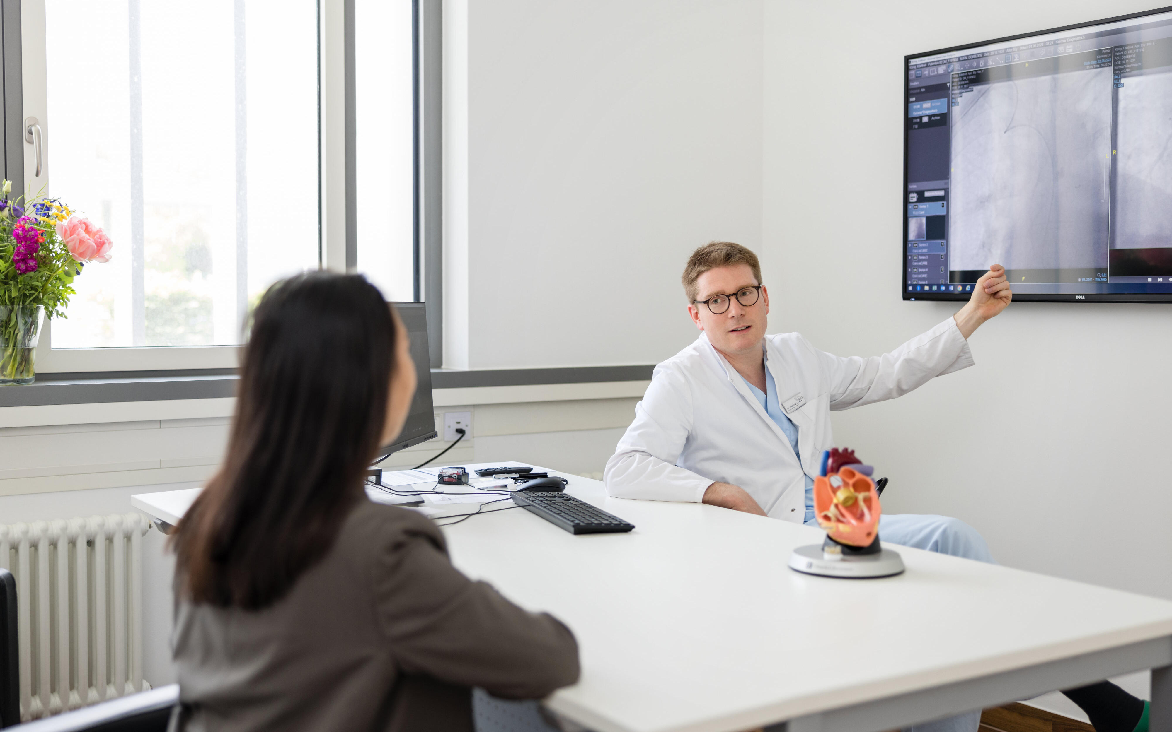 Ein Facharzt erklärt einer Patientien etwas auf einem Monitor
